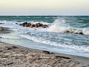 A beach with waves crashing onto rocks and a sandy shore. - 6 Person Holiday Home in Otterup (Otterup)