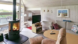 A cozy living room with a wood-burning stove, a sofa, a TV, and a dining area. - 6 Person Holiday Home in Otterup (Otterup)