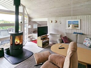 A cozy living room with a wood-burning stove, a sofa, a TV, and a dining area. - 6 Person Holiday Home in Otterup (Otterup)