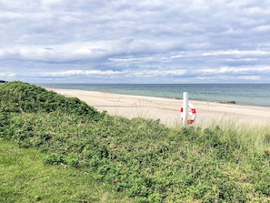 A beach with a lifebuoy, grassy area, and the sea. - 6 Person Holiday Home in Otterup (Otterup)