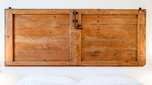 Un lit avec une literie blanche et une tête de lit en bois dotée d’un loquet.