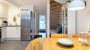 Une cuisine moderne dotée d’un réfrigérateur en acier inoxydable, de meubles en bois et d’un coin repas avec une table et des chaises en bois.