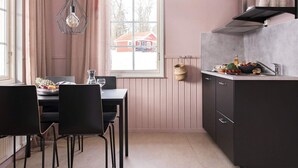 A compact kitchen with a dining table and chairs, a window with a view of a red house, and a hanging light fixture. - 4 Star Holiday Home in Garsnas (Gärsnäs)