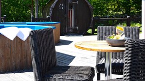 A wooden deck with a hot tub, wicker furniture, and a glass of orange juice on a table. - 4 Star Holiday Home in Garsnas (Gärsnäs)