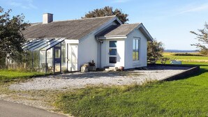 A modern house with a sloped roof, a glass conservatory, and a gravel driveway. - 4 Person Holiday Home in Hurup Thy (Hurup Thy)