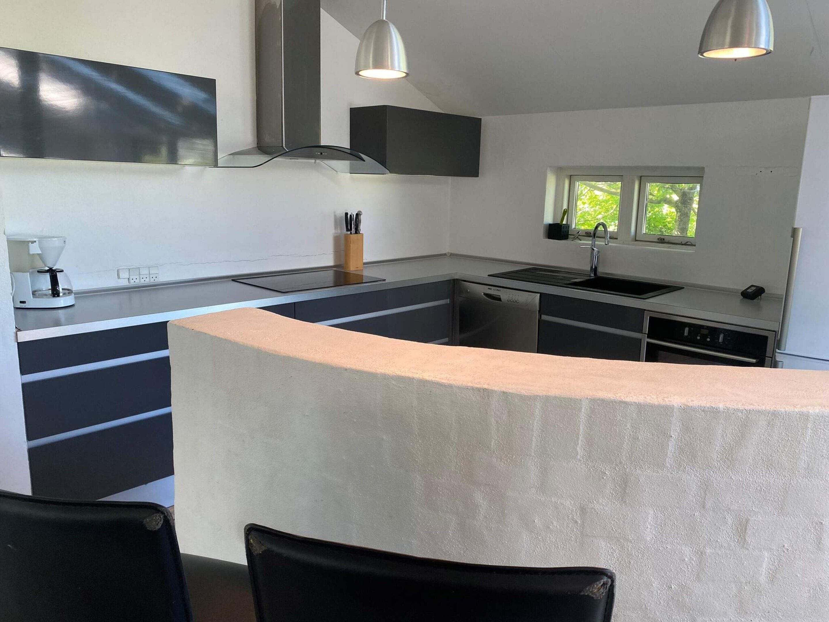 A modern kitchen with a central island, built-in appliances, and pendant lighting.