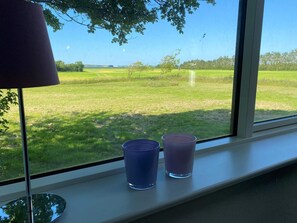 A window with a view of a grassy field and a lamp on the window sill. - 4 Person Holiday Home in Hurup Thy (Hurup Thy)