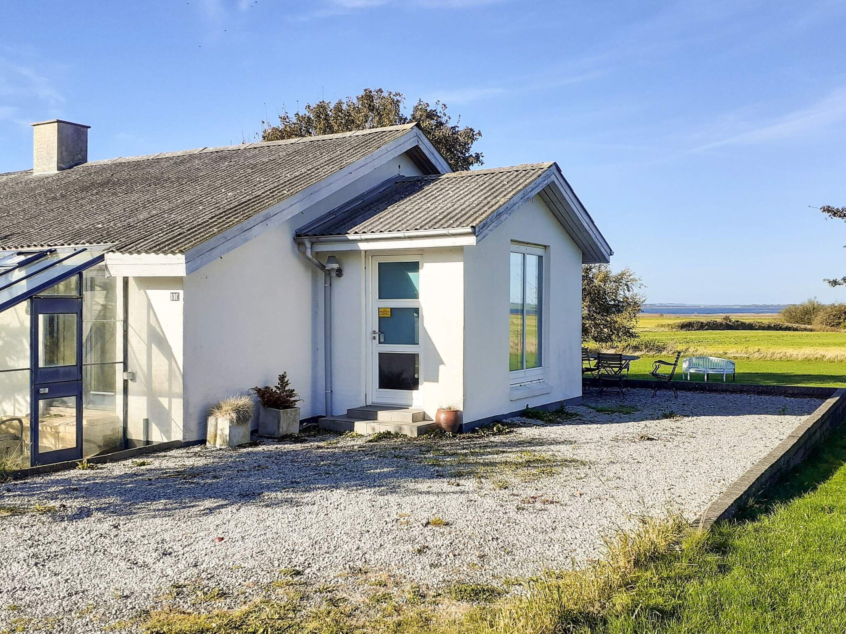 A single-story house with a sloped roof, a front porch, and a gravel driveway.