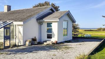 A single-story house with a sloped roof, a front porch, and a gravel driveway.