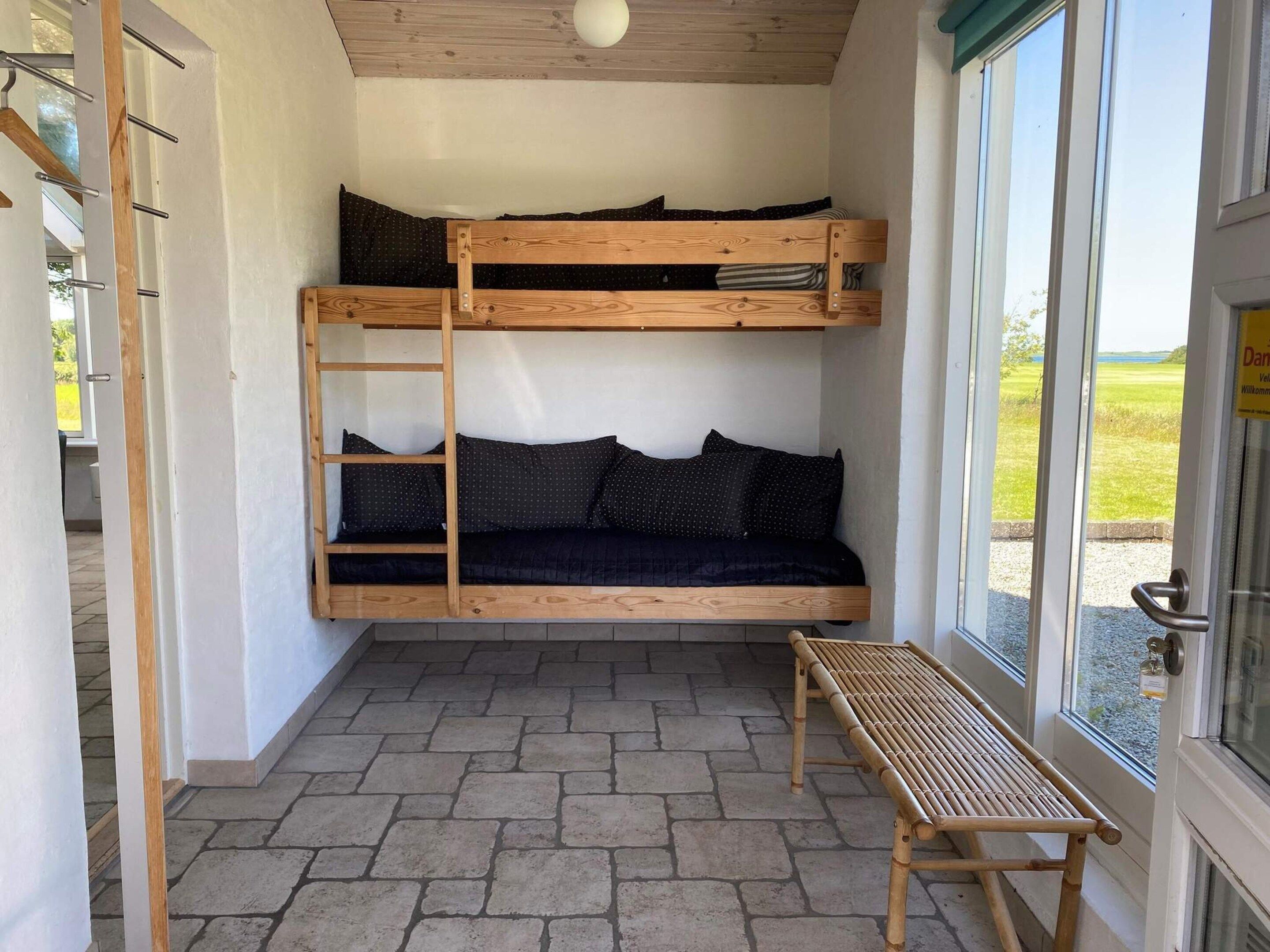 A bunk bed with a ladder, a bench, and a door with a sign.
