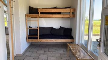 A bunk bed with a ladder, a bench, and a door with a sign.
