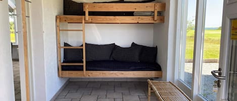 A bunk bed with a ladder, a bench, and a door with a sign.