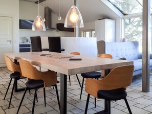 A modern kitchen with a dining area, featuring a large table, chairs, pendant lights, and a sofa. - 4 Person Holiday Home in Hurup Thy (Hurup Thy)