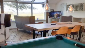 Una mesa de billar con una bola blanca, rodeada de sillas modernas y una mesa de comedor.