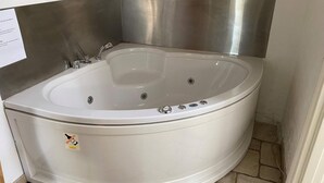 A corner bathroom with a white bathtub, a stainless steel sink, and a tiled floor. - 4 Person Holiday Home in Hurup Thy (Hurup Thy)