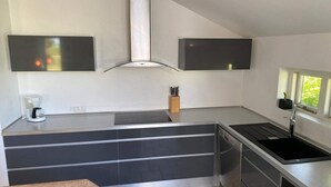Una cocina moderna con estufa integrada, cafetera y bloque de cuchillos.