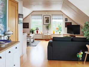 A cozy loft apartment with a dining area, a living room with a sofa, and a television. - 4 Star Holiday Home in Frillesas (Frillesas)