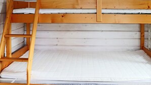 Un lit superposé avec une échelle, du linge de lit blanc et une tête de lit en bois.