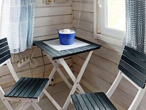 A small room with a foldable table and two chairs, a blue bucket on the table, and a window with curtains. - 4 Star Holiday Home in Frillesas (Frillesas)