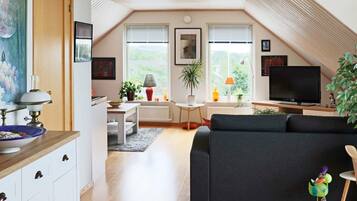 Un loft moderno con comedor, sala de estar con sofá, televisión y cocina con gabinetes y encimera.