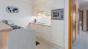 A compact kitchen with a microwave, stove, and sink. - Apartment in Middelkerke Near Sandy Beach (Middelkerke)