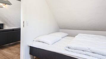 A bedroom with a bed, a bedside table, and a light fixture on the ceiling.