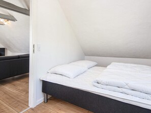 A bedroom with a bed, a bedside table, and a light fixture on the ceiling.