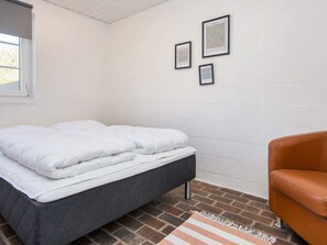 A bedroom with a bed, a chair, and a brick floor. - 8 Person Holiday Home in Romo (Rømø)