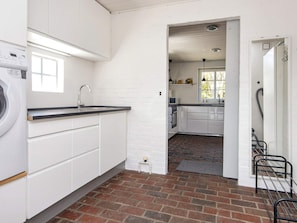 A laundry area with a washing machine, a sink, and a brick floor. - 8 Person Holiday Home in Romo (Rømø)