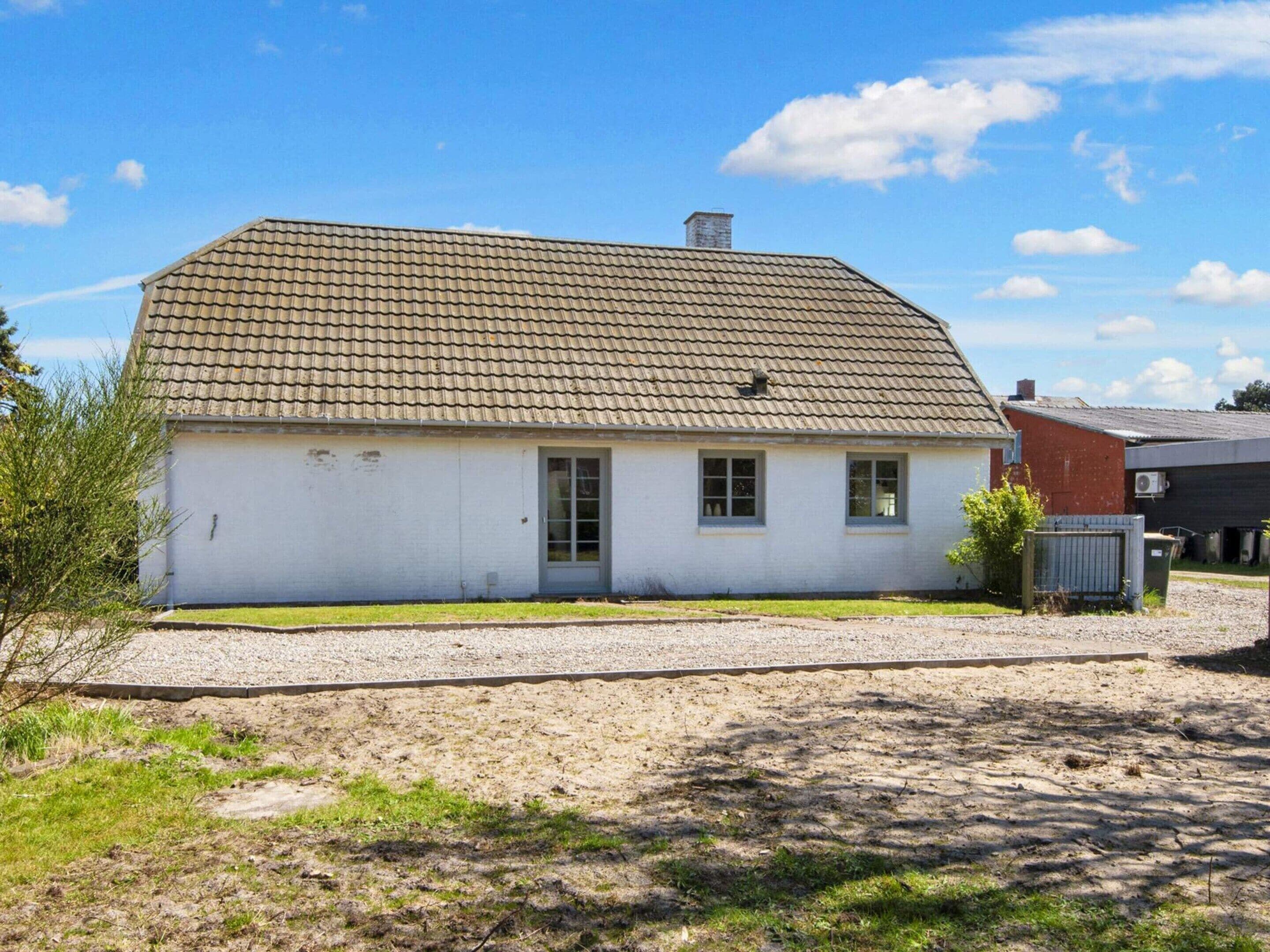 Ein eingeschossiges Haus mit Ziegeldach, Haustür und kleiner Veranda.