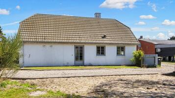 A single-story house with a tiled roof, a front door, and a small porch.