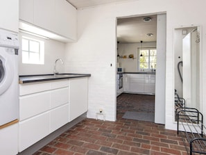 A laundry area with a washing machine, a sink, and a brick floor. - 8 Person Holiday Home in Romo (Rømø)