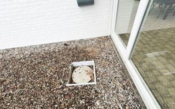 A gravel-covered ground with a white drain cover. - 8 Person Holiday Home in Romo (Rømø)