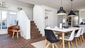 A modern kitchen with white cabinets, a stainless steel refrigerator, and black pendant lights. - 8 Person Holiday Home in Romo (Rømø)