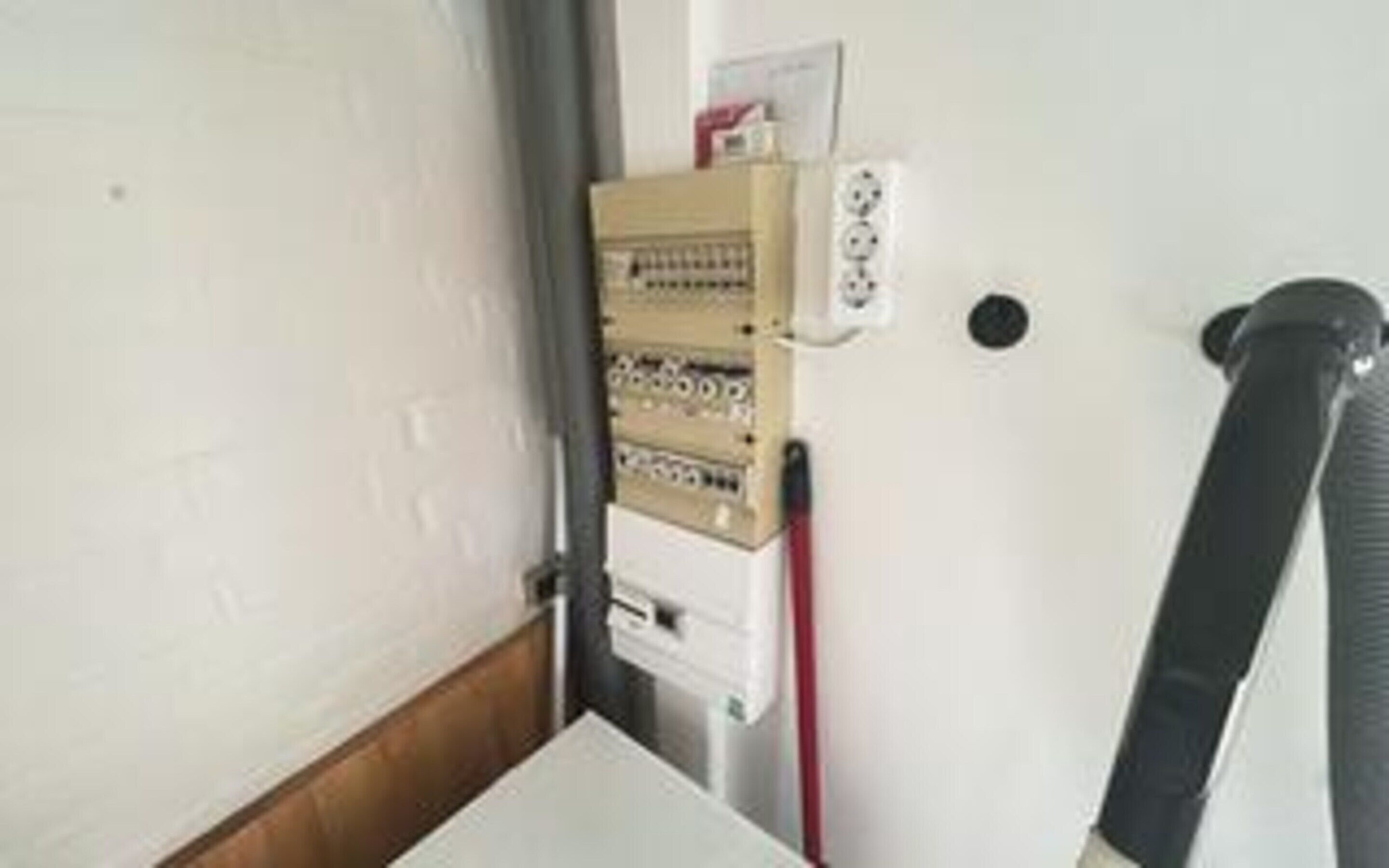 A room with a white wall, a wooden door, and a whiteboard with some writing.