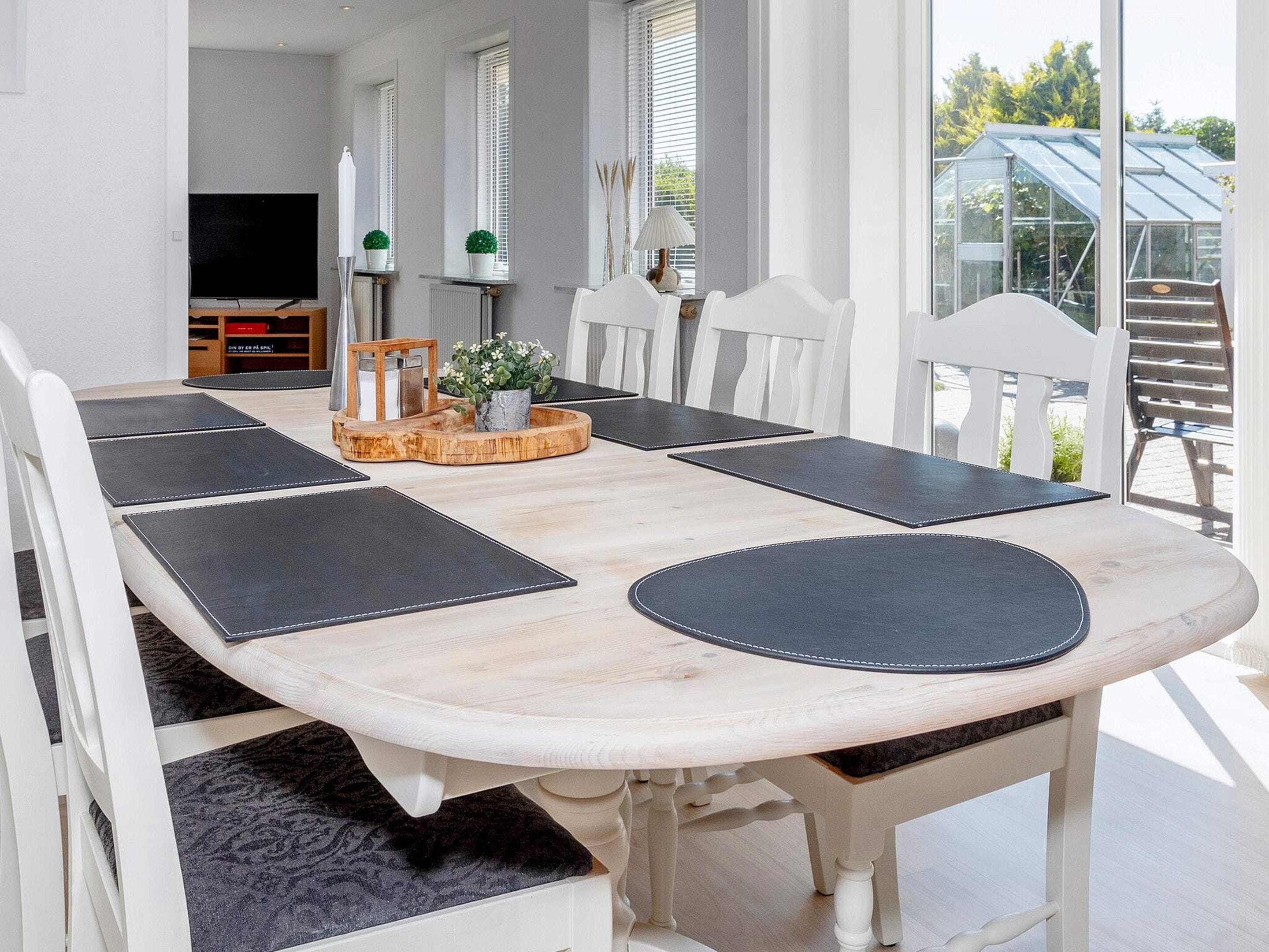 En matplats med ett träbord, vita stolar och svarta bordsunderlägg.