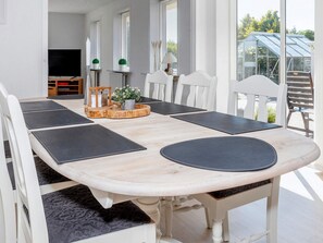 Un comedor con una mesa de madera, sillas blancas y manteles individuales negros.