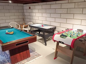 A pool table, foosball table, and a table tennis table in a room with brick walls and white chairs. - 4 Star Holiday Home in Blokhus (Blokhus)