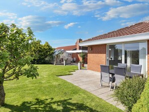 A residential property with a brick exterior, a glass conservatory, and a patio with outdoor furniture. - 4 Star Holiday Home in Blokhus (Blokhus)