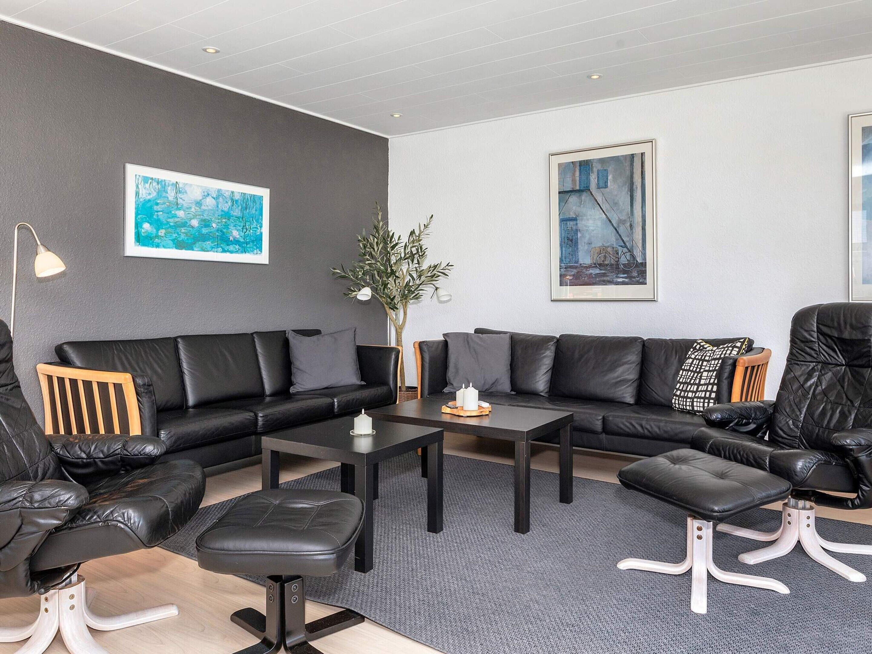 A modern living room with a sectional sofa, a coffee table, and a side table. There is a potted plant and artwork on the walls.