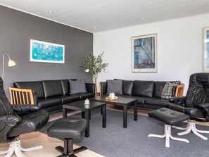 A modern living room with a sectional sofa, a coffee table, and a side table. There is a potted plant and artwork on the walls.