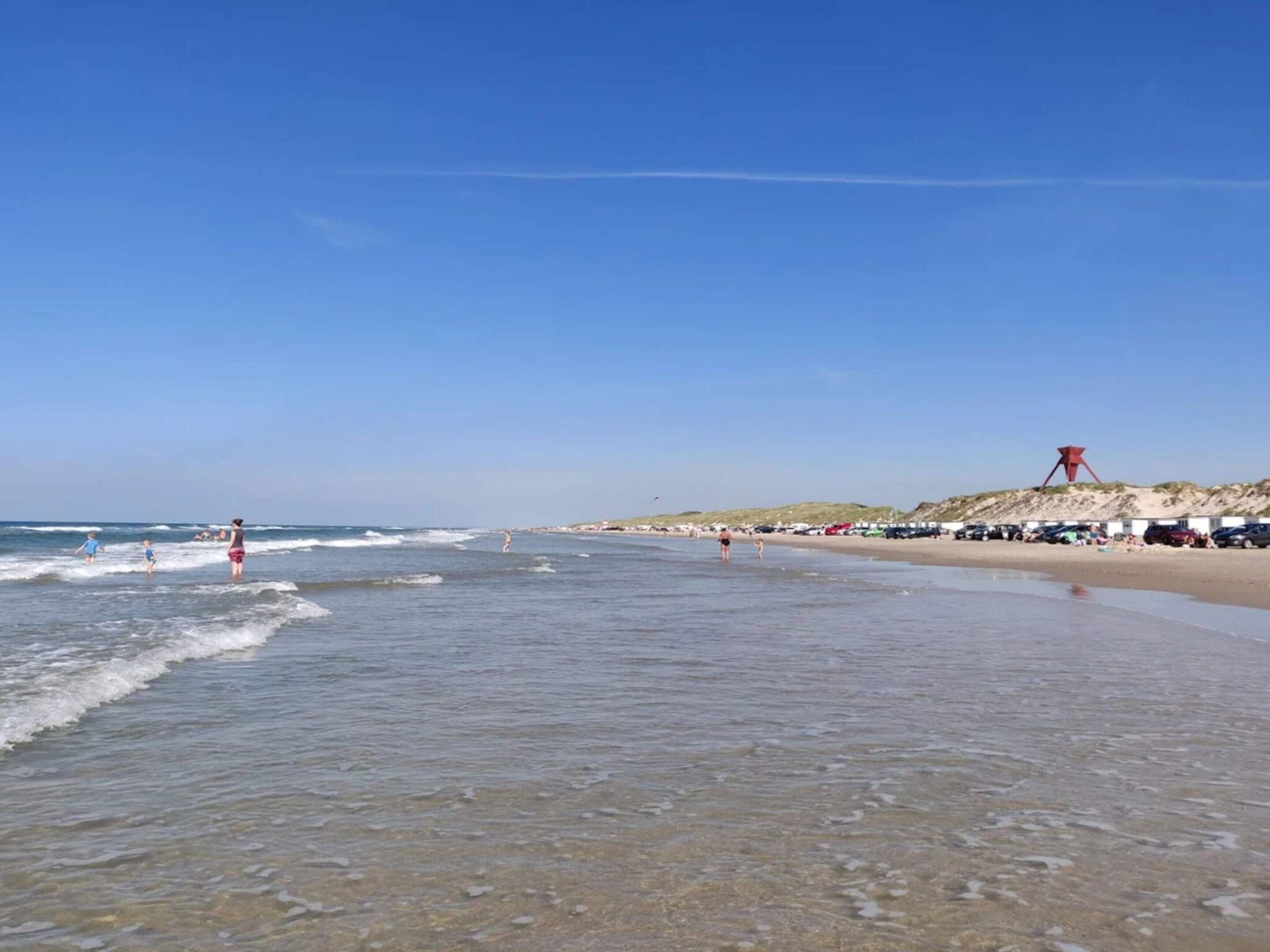 Een strand met heldere lucht, rustig water en een zandstrand.