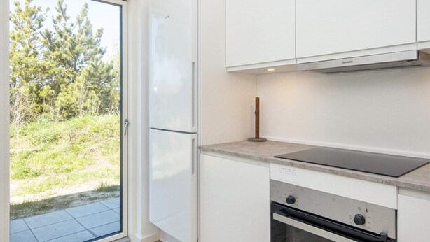 A modern kitchen with a built-in oven, a stovetop, and a refrigerator. - 5 Star Holiday Home in Romo (Rømø)