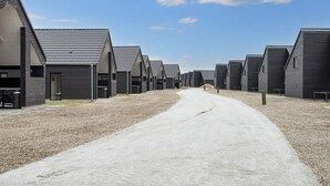 A row of modern, dark-colored buildings with a gravel path leading through them. - 5 Star Holiday Home in Romo (Rømø)
