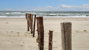 A sandy beach with wooden posts and the ocean in the background. - 5 Star Holiday Home in Romo (Rømø)