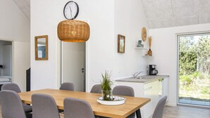 A modern kitchen with a dining area, a clock, and a view of greenery outside. - 5 Star Holiday Home in Romo (Rømø)