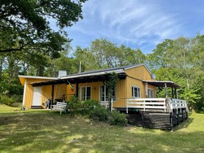 A wooden cabin with a porch, a covered deck, and a small garden area. - 4 Star Holiday Home in Ramdala (Ramdala)