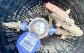 Een mechanisch apparaat met buizen en een rond onderdeel, mogelijk een ventiel of een pomp, met een blauw label.