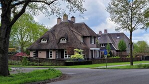 A traditional thatched-roof house with a brick extension, surrounded by greenery and a clear sky. - Villa in Overloon Near War Museum (Overloon)