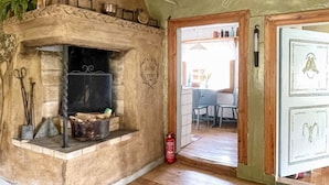 A rustic kitchen with a stone oven, a fire extinguisher, and a wooden door with decorative panels. - 4 Person Holiday Home in Kolmarden (Kolmården)